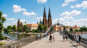 A professional editorial photograph of a sunny Wrocław cityscape featuring the iconic Ostrów Tumski
