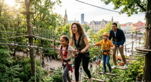 A high-quality, editorial shot of a cheerful family navigating a scenic rope course in a lush Wrocła