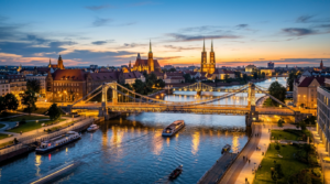 A professional, editorial-style wide shot of Wrocław’s illuminated bridges over the Oder River at go