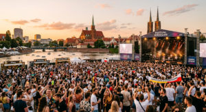 A high-quality, editorial-style photograph of a lively outdoor summer music festival in Wrocław, fea